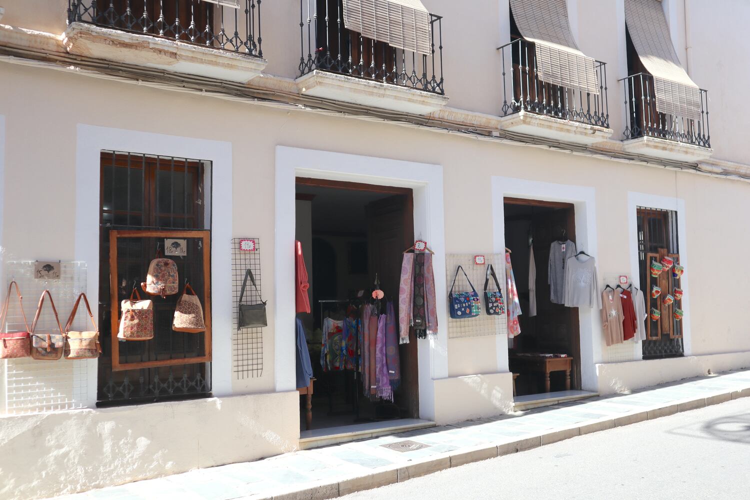 A street view of a quaint shop front with traditional clothing and souvenirs on display in an old European town.