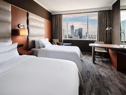 Hotel bedroom with city view and minimalist decor.