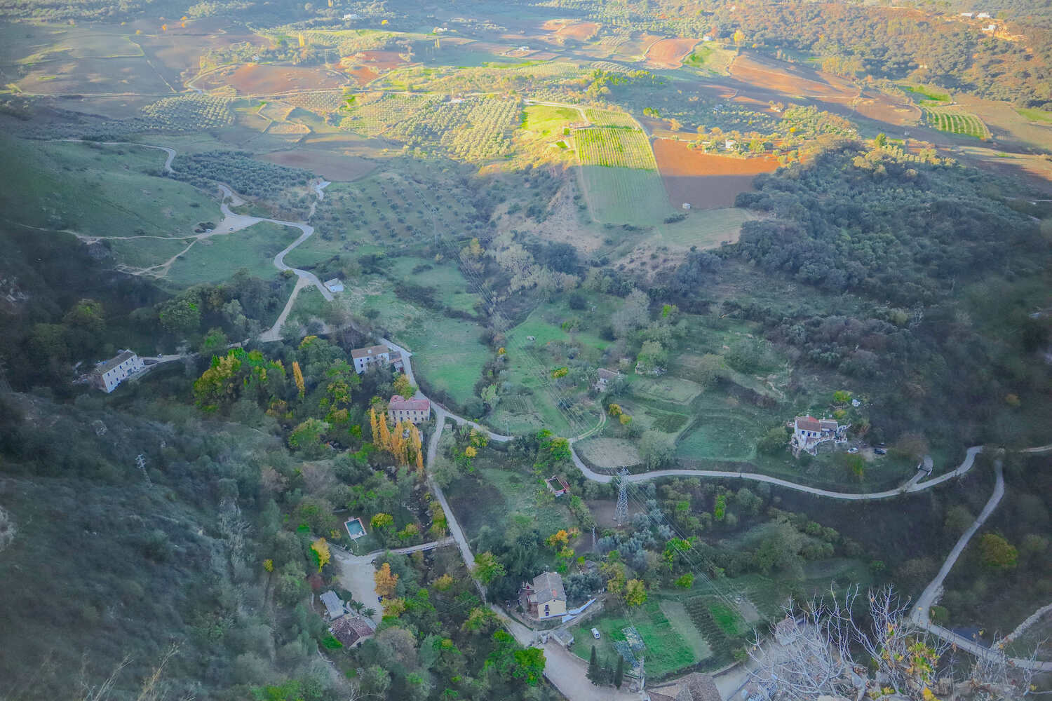 Aerial shot of a verdant valley with patchwork fields and meandering river, surrounded by gentle hills