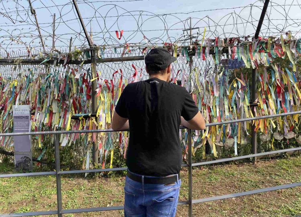 Man photographing hanging colorful ribbons at the border between North and South Korea